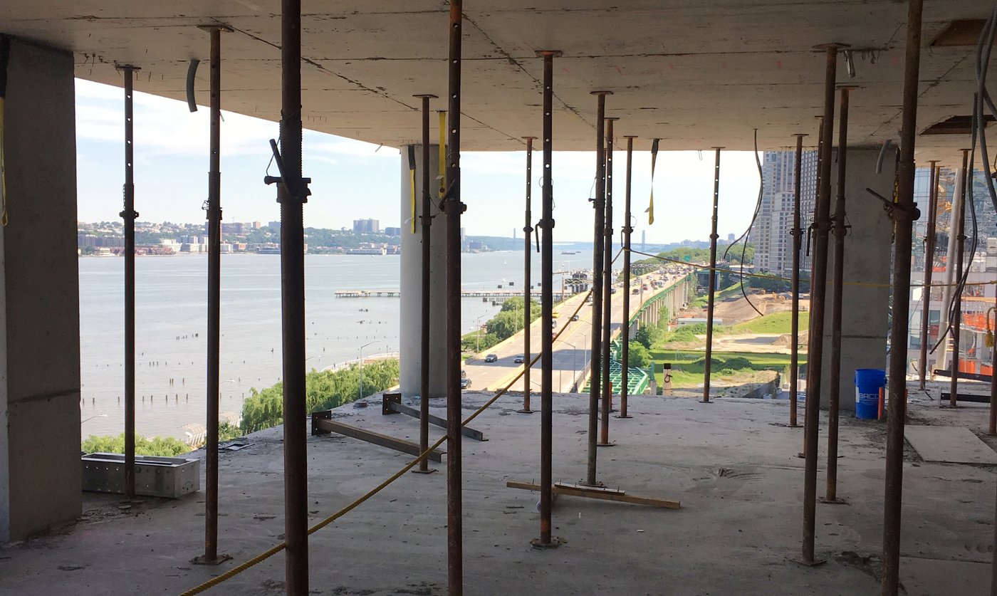 Adjustable steel post shores under a concrete slab on an upper floor, river visible beyond